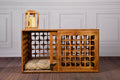 Wooden pet crate with lattice design on a wooden floor against a gray paneled wall.